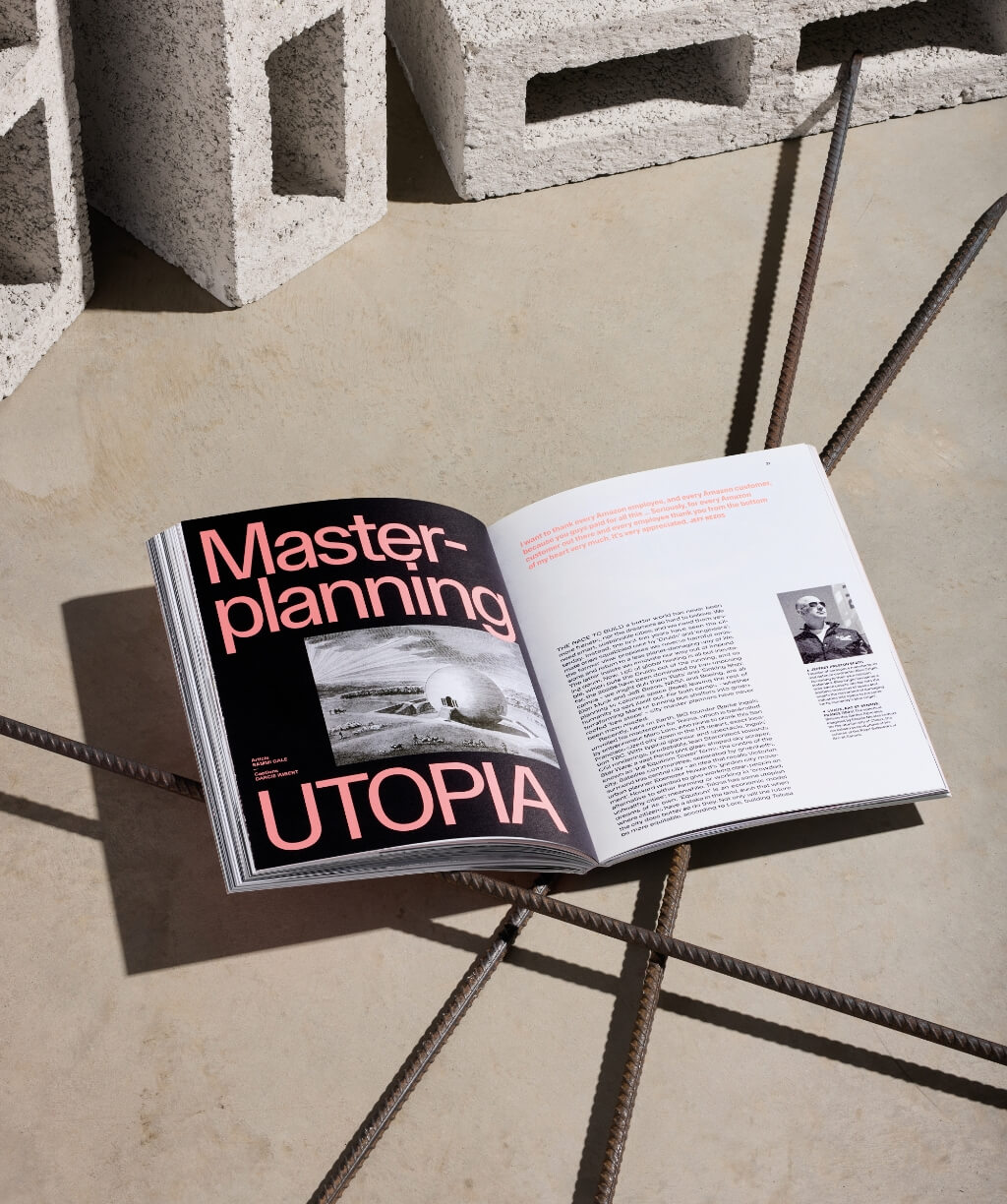 An open magazine spread featuring bold coral-pink slab-serif typography reading "Masterplanning UTOPIA" over a black-and-white aerial photograph, with text and a portrait on the right page.